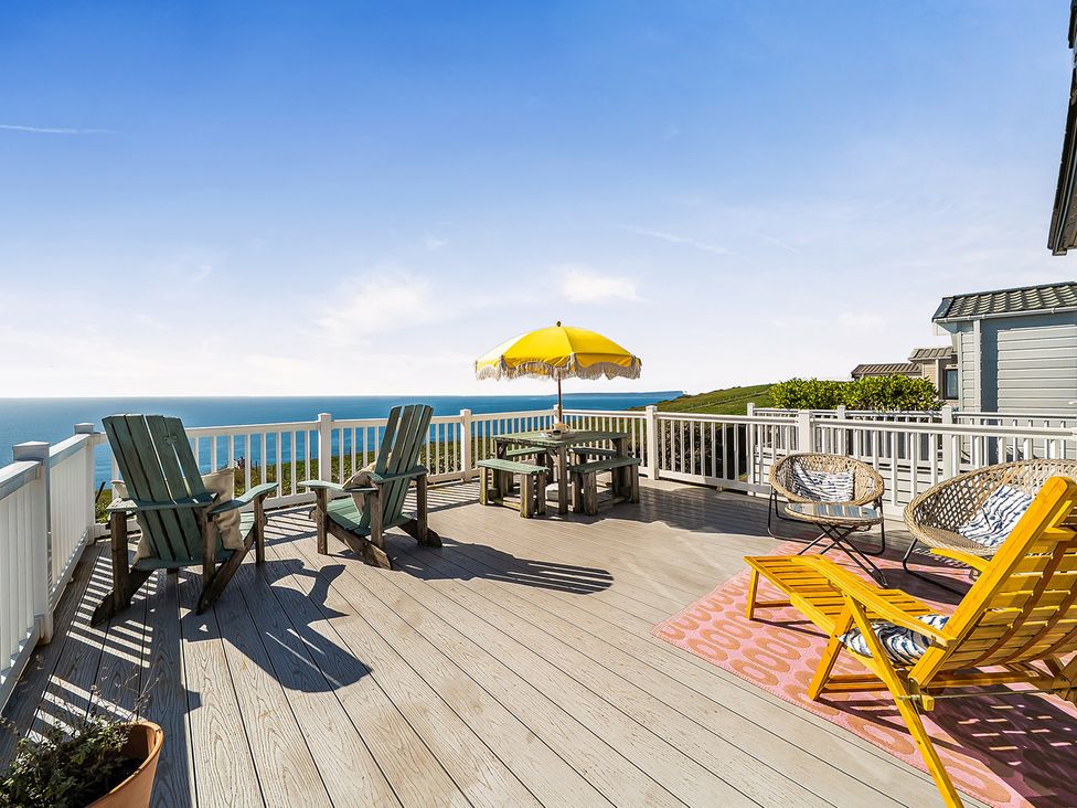 A deck with seating and a table with an umbrella at 2 Bed Caravan, Sleeps 4 with Sea Views, West Lulworth