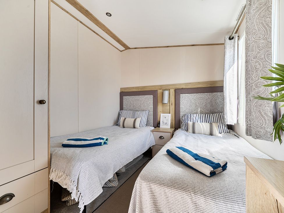 A bedroom with twin beds and a nightstand at 2 Bed Caravan, Sleeps 4 with Sea Views West Lulworth