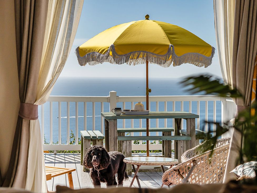 A patio with a table and a yellow umbrella overlooking the sea at 2 Bed Caravan, Sleeps 4 with Sea Views, West Lulworth