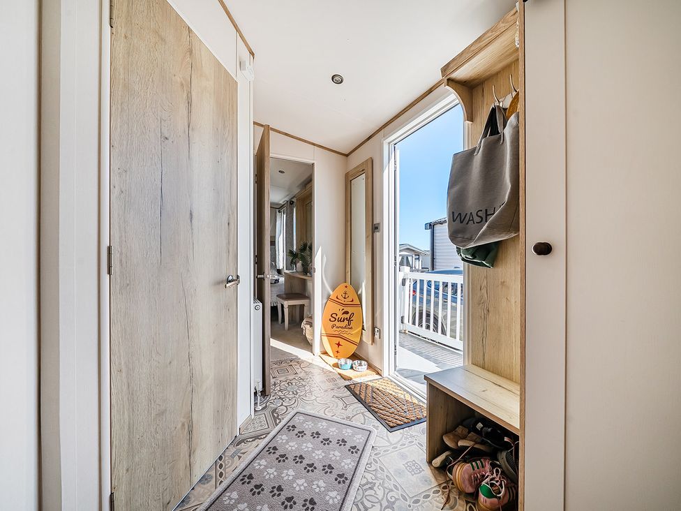 A hallway with a surfboard and shoes organized at 2 Bed Caravan, Sleeps 4 with Sea Views in West Lulworth