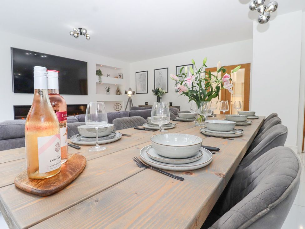 A dining room with a wooden table and wine bottles at Berisal in Ashford