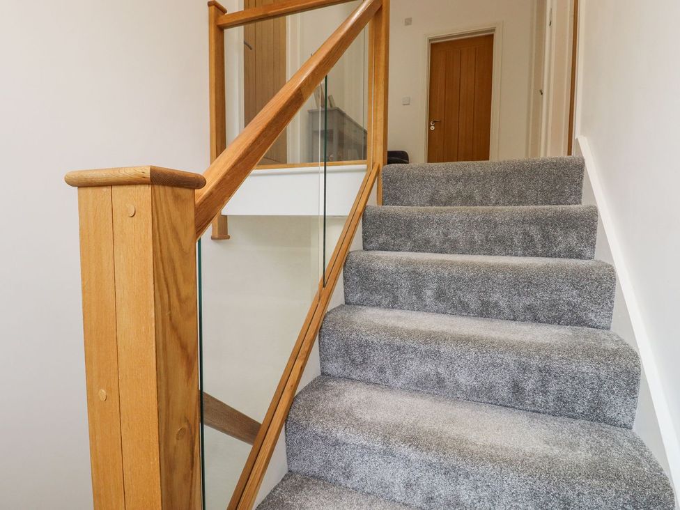 Stairs with wooden handrail and door at Berisal Ashford