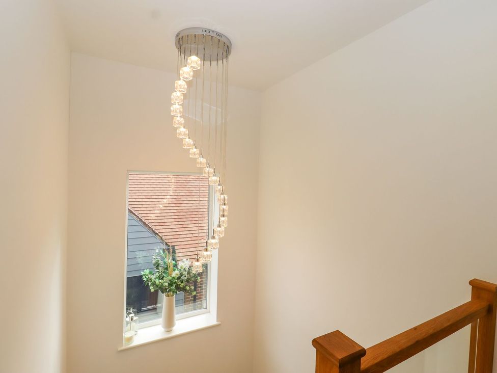 A stairwell with a chandelier and a window at Berisal in Ashford
