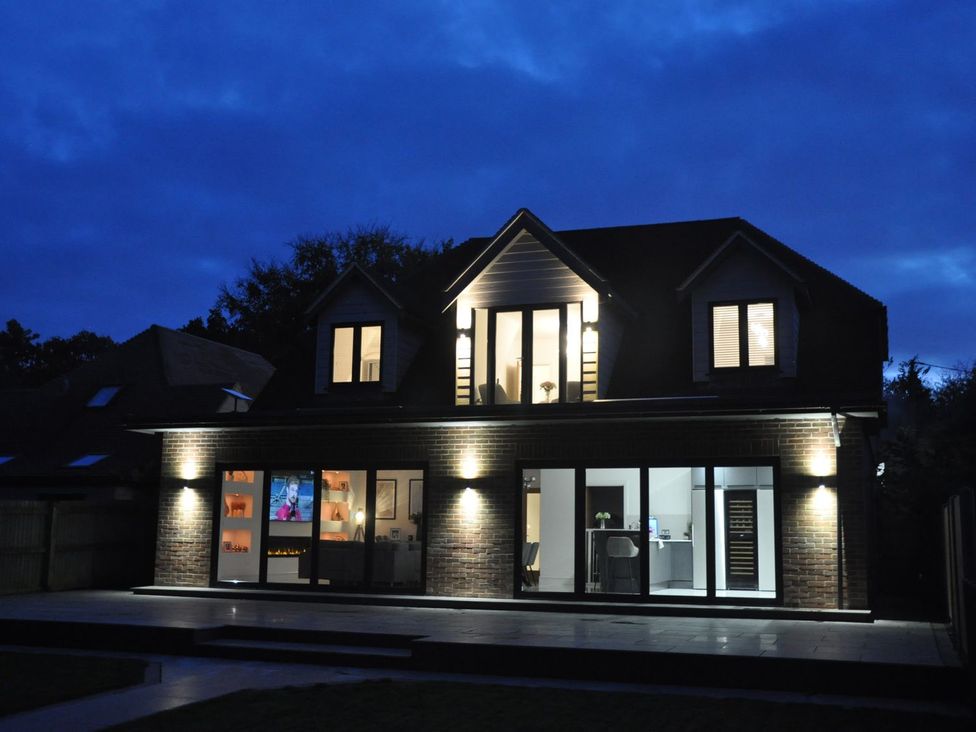 A house with illuminated windows and patio at Berisal in Ashford