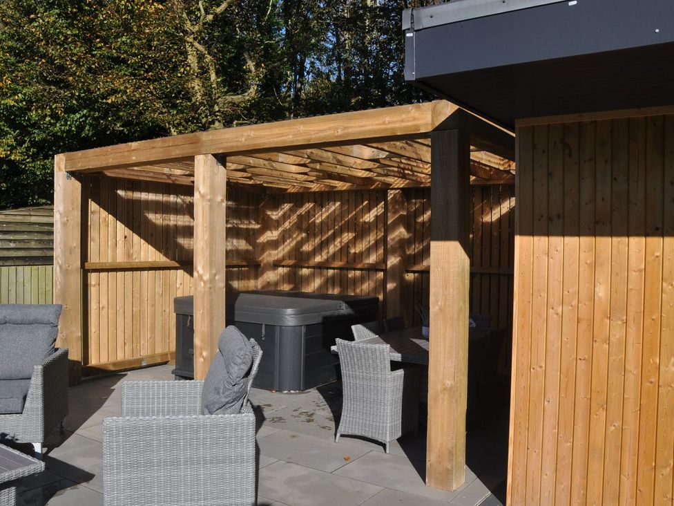 An outdoor patio with a hot tub and seating at Berisal in Ashford