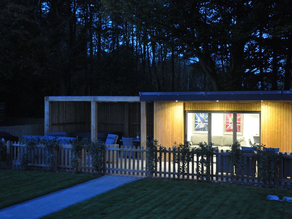A building with windows illuminated outside and a path at Berisal in Ashford