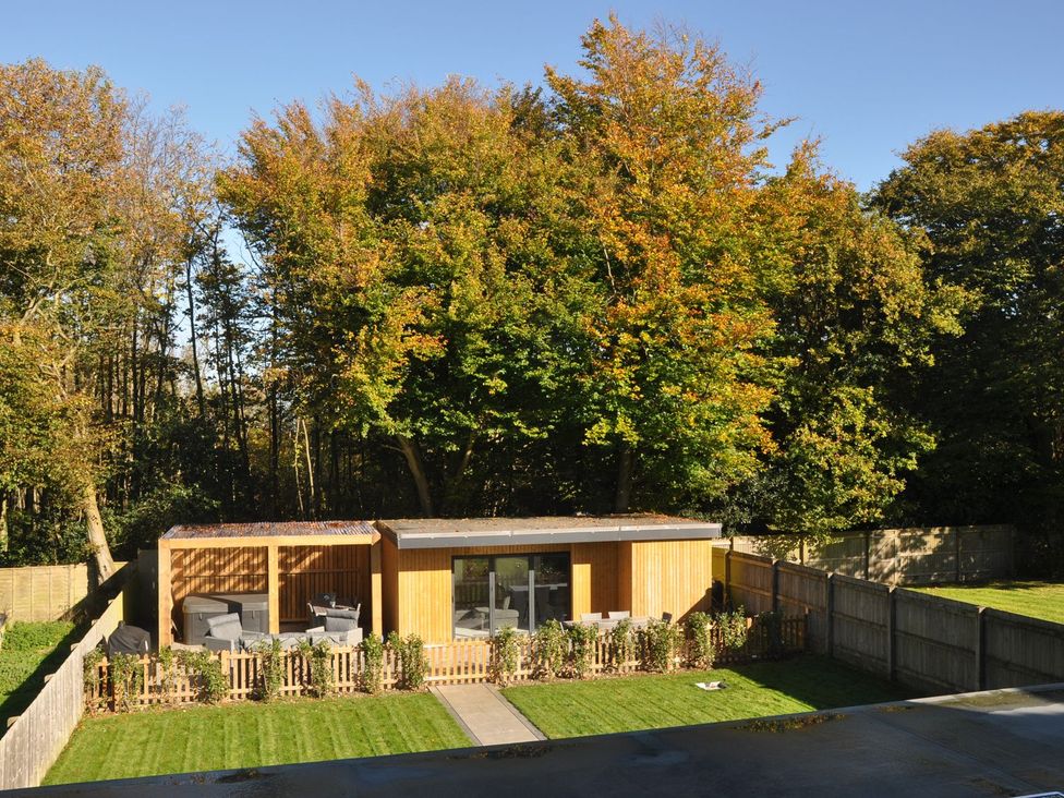 A wooden cabin with outdoor seating at Berisal in Ashford