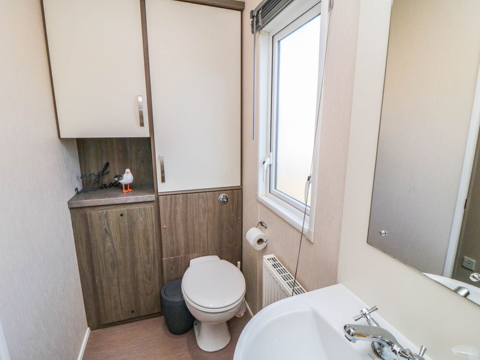 A bathroom with a toilet, sink, and mirror at Gosling 14 in Scarborough