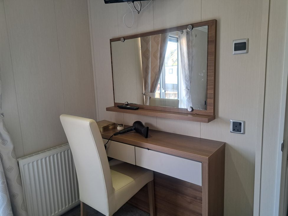 A vanity with a mirror and chair at Chapel Farm Static Caravan Holiday Park Lucky Lodge 7 Appleby-in-Westmorland
