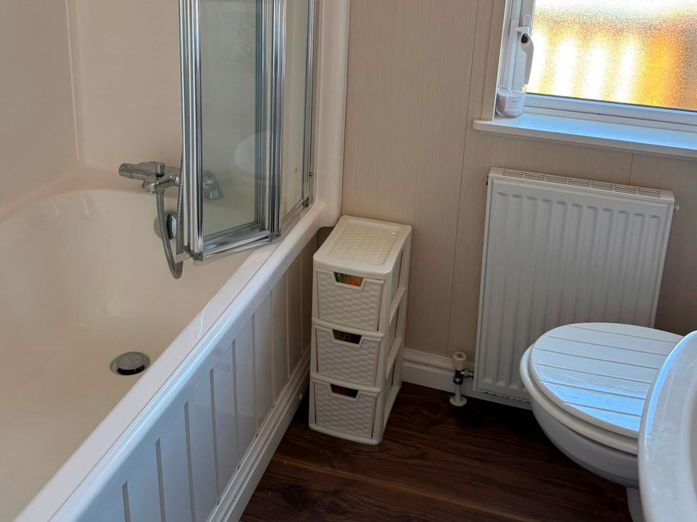 A bathroom with a bathtub, toilet, and storage unit at Chapel Farm Static Caravan Holiday Park Lucky Lodge 7 Appleby-in-Westmorland