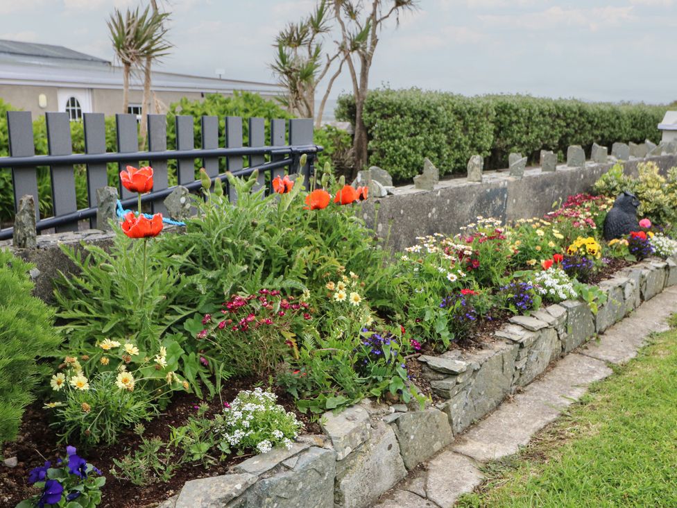 A garden with flowers and a stone wall at Wild Atlantic Way Country Cottage, Portmagee, County Kerry