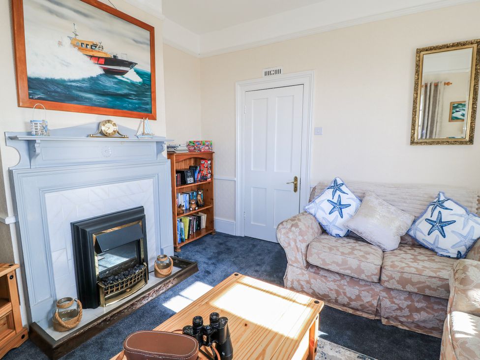 A living room with a fireplace and a bookshelf at Old Higher Lighthouse Stopes Cottage in Portland Bill