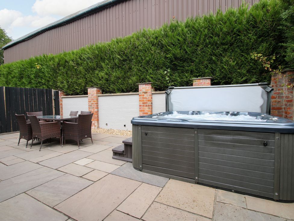 A patio with a hot tub and dining set at The Turnip House in Westhope