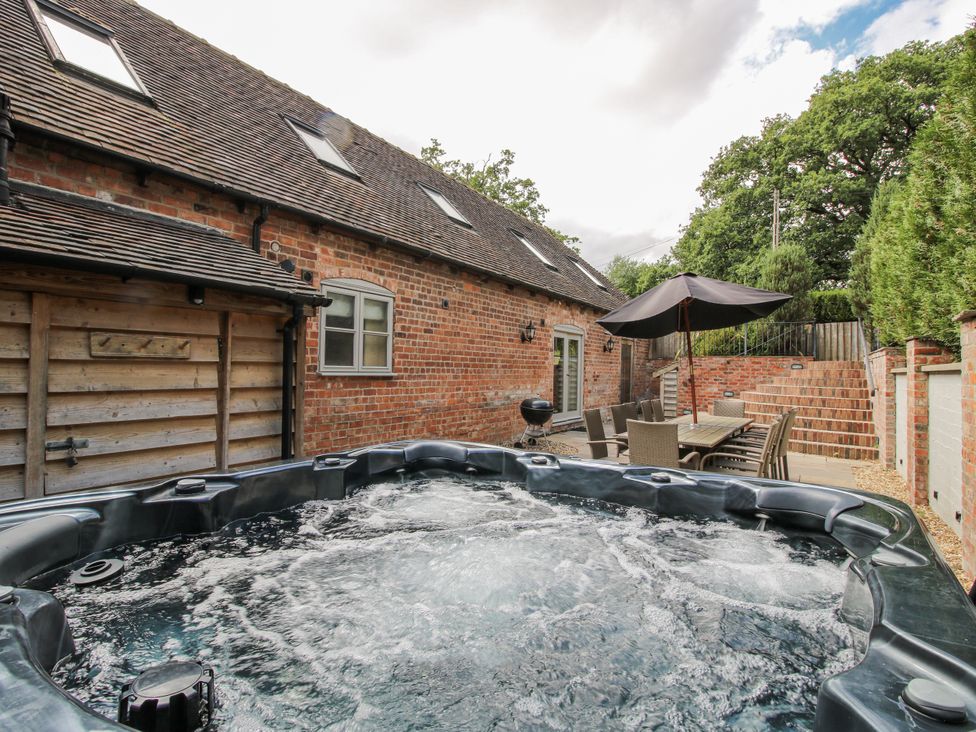An outdoor area with a hot tub, table and chairs at The Milking Parlour in Westhope