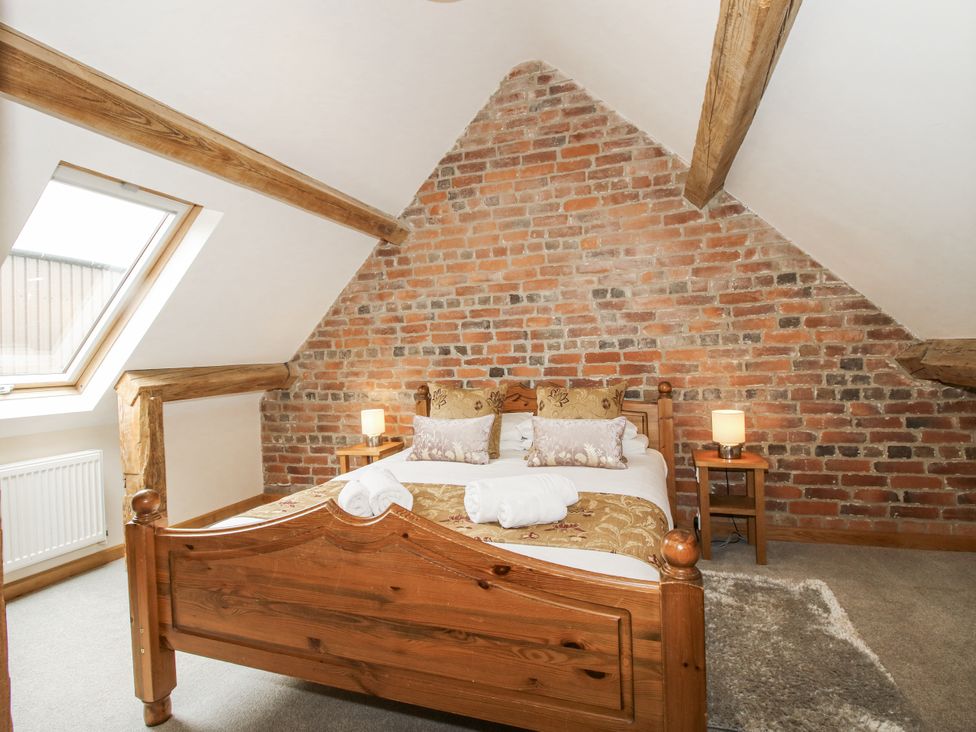 A bedroom with a bed, nightstand, and window at The Milking Parlour in Westhope