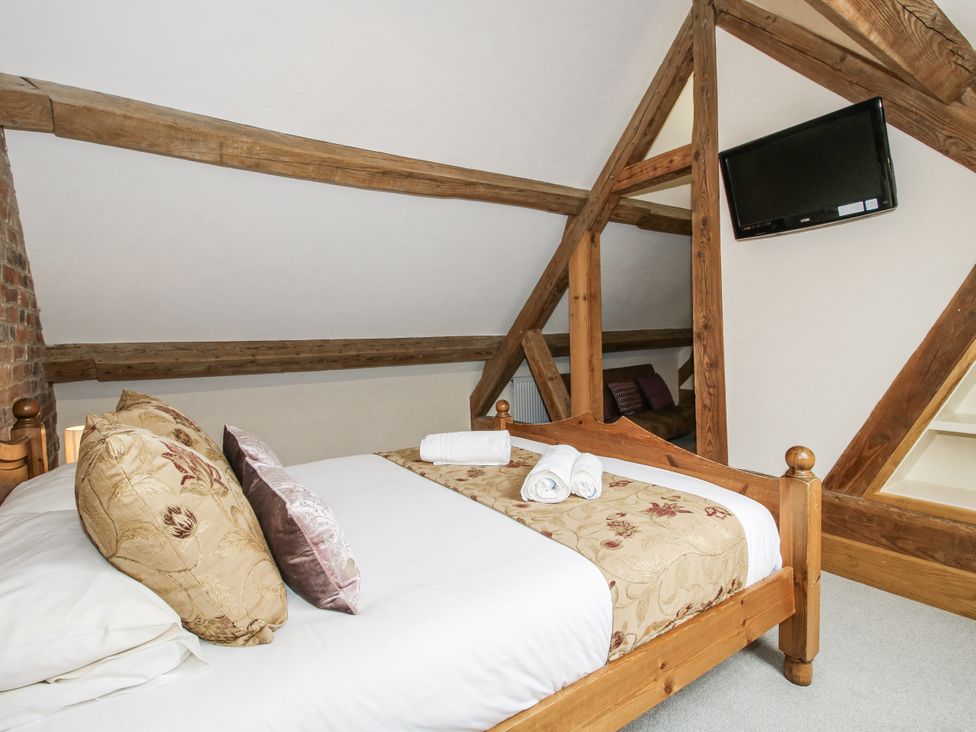 A bedroom with a bed, pillows, towels, and a television at The Milking Parlour in Westhope