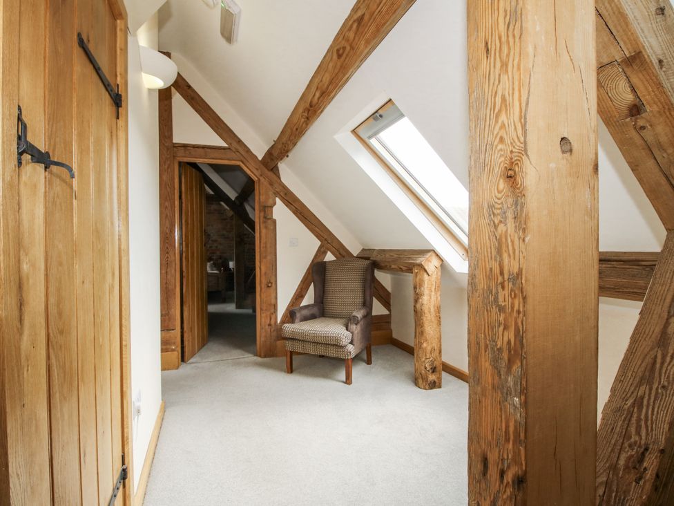 An attic with wooden beams and a chair at The Milking Parlour Westhope