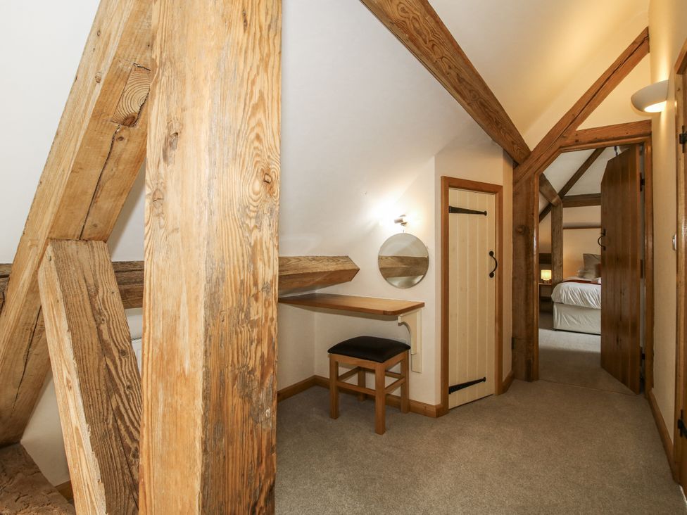 A bedroom with wooden beams, a desk, and a chair at The Milking Parlour in Westhope