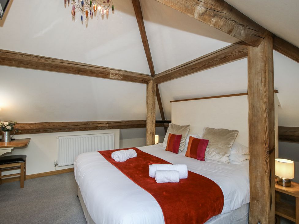 A bedroom with a bed, chandelier, chair and table at The Milking Parlour in Westhope