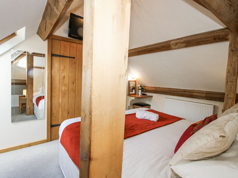 A bedroom with a bed, mirror, and table at The Milking Parlour in Westhope
