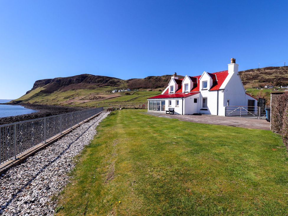 A house by the sea with a cliff in the background at Jubilee Cottage Uig
