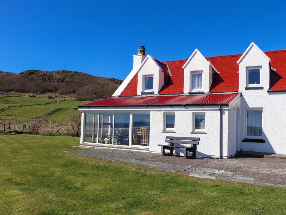 A house with a glass extension and mountain view at Jubilee Cottage in Uig