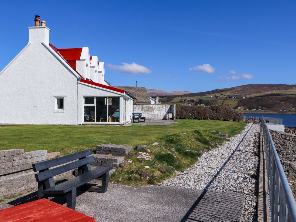A house with a garden and pathway by the water at Jubilee Cottage Uig
