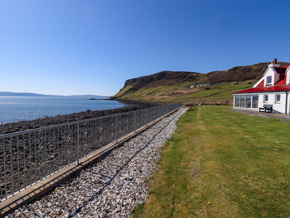 A view along the shoreline with a house by the sea at Jubilee Cottage Uig