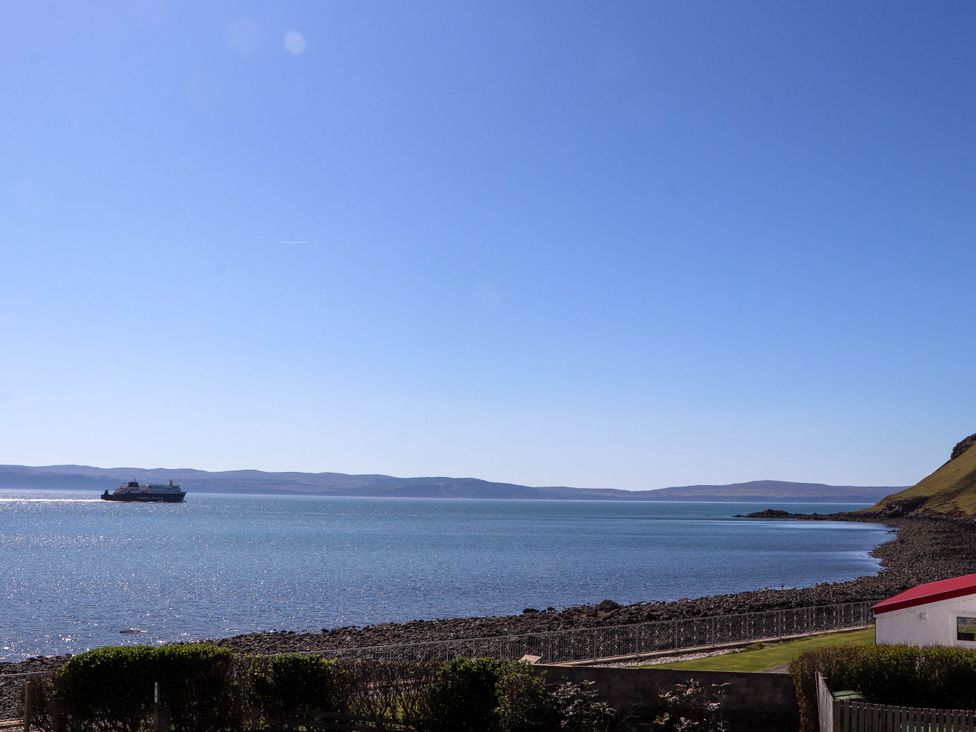 A coastal scene with a boat on the water at Jubilee Cottage in Uig