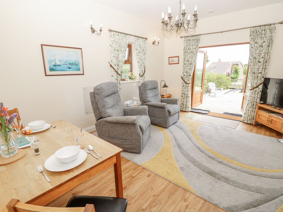 A living room with a dining area and sliding doors at 2 The Stables in Ryde