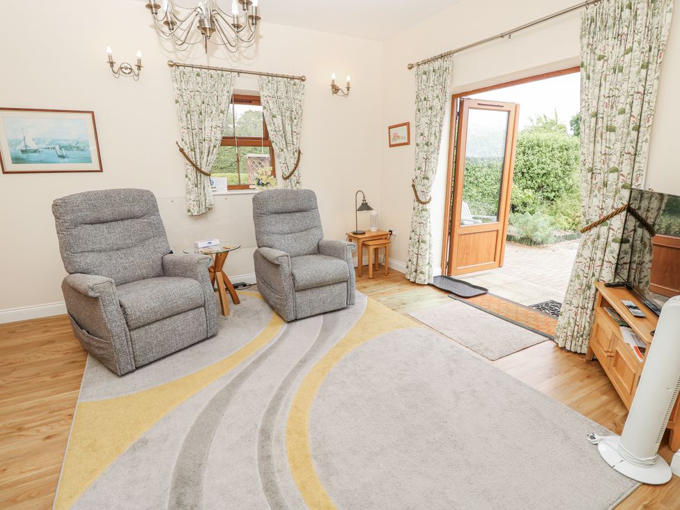 A living room with armchairs and a door leading to a garden at 2 The Stables Ryde