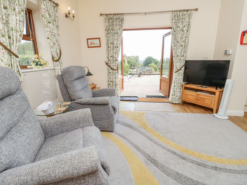 A living room with two armchairs and a television at 2 The Stables in Ryde