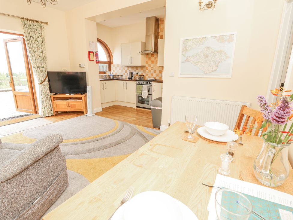 A dining room with kitchen and sofa at 2 The Stables in Ryde