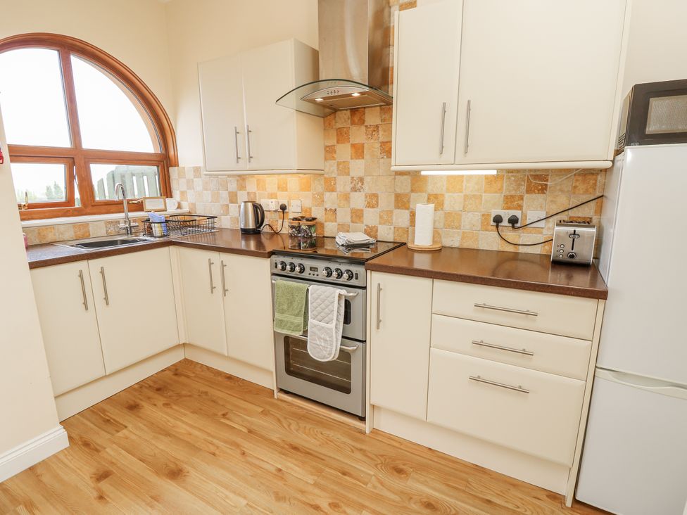 A kitchen with a stove, sink, and countertop at 2 The Stables in Ryde