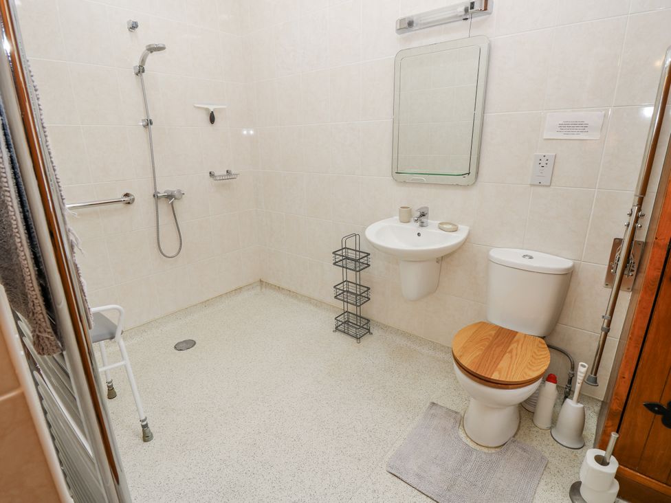 A bathroom with a shower, toilet, and sink at 2 The Stables Ryde