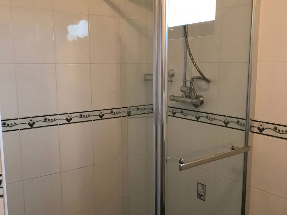 A shower enclosure with tiled walls and a glass door at Primrose Lodge in Saltburn-by-the-Sea