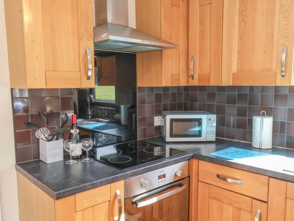 A kitchen with cabinets, a microwave, and wine glasses at Primrose Lodge in Saltburn-by-the-Sea