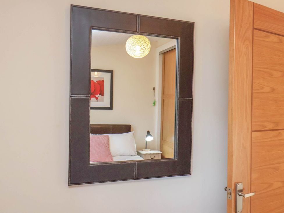 A mirror reflecting a bed and lamp at Primrose Lodge in Saltburn-by-the-Sea