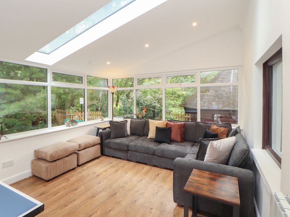 A conservatory with a sofa and windows at Eden House in Bardsea