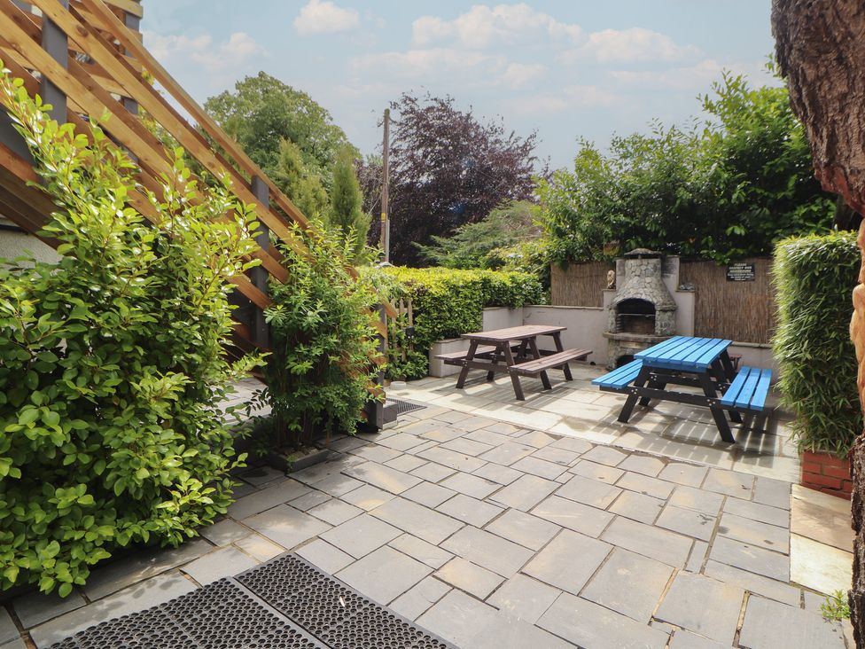 A garden with seating and a barbecue at Eden House in Bardsea