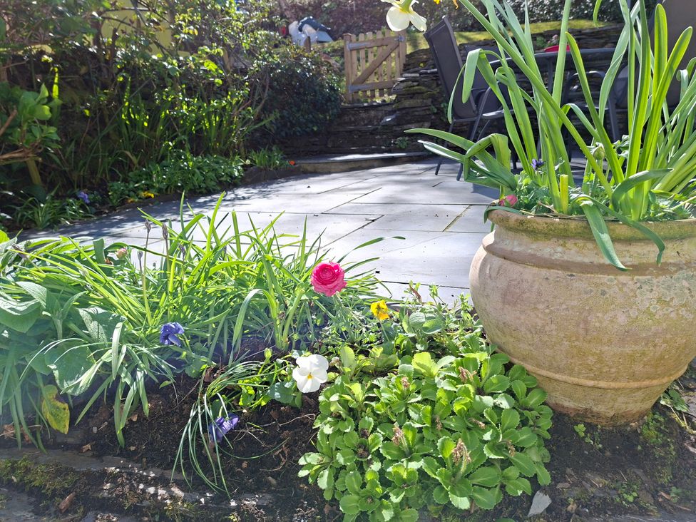 A garden with flowers and a stone patio at Llannor in Borth-y-Gest