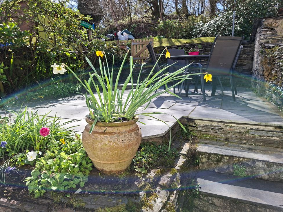 A garden with a flower pot and table and chairs at Llannor in Borth-y-Gest