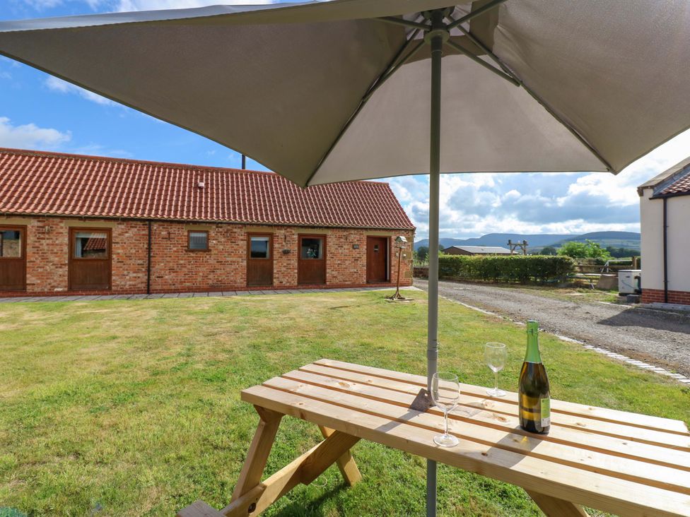 An outdoor seating area with a table and glasses at Pottowe Cottage in Potto near Stokesley