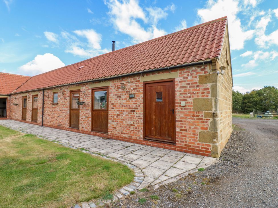 An exterior view of a cottage with a brick facade and pathway at Pottowe Cottage in Potto near Stokesley