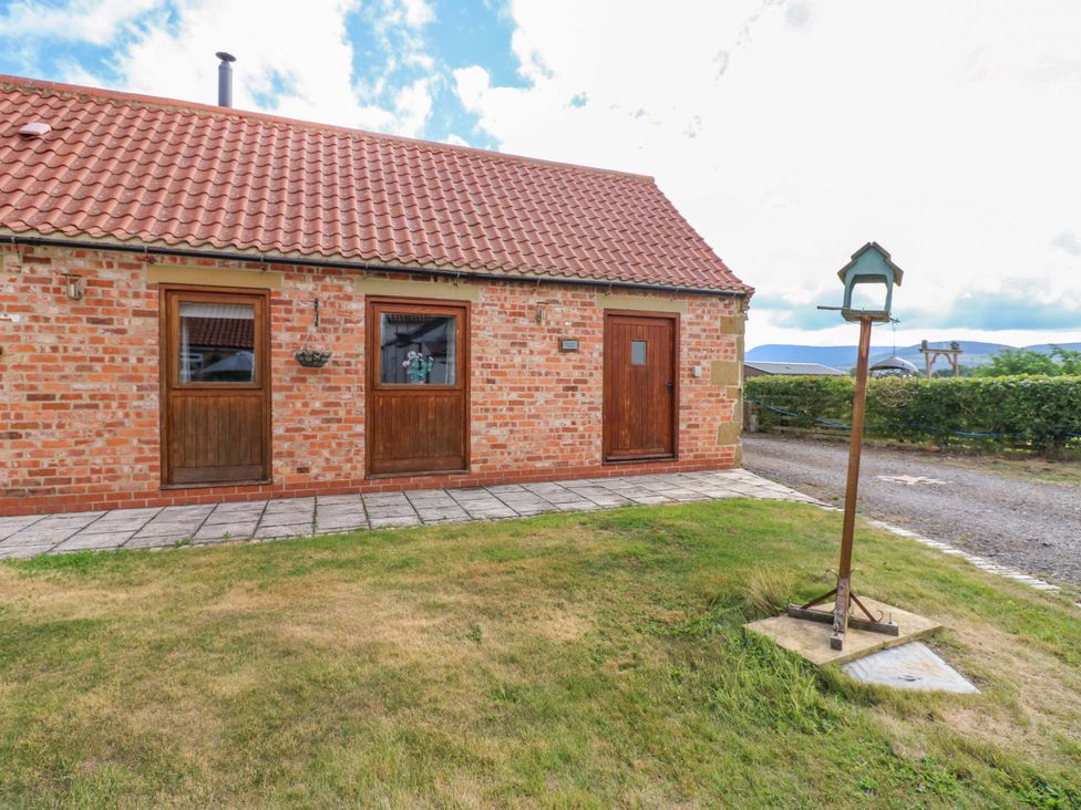 A brick exterior of a cottage with doors and windows at Pottowe Cottage in Potto near Stokesley