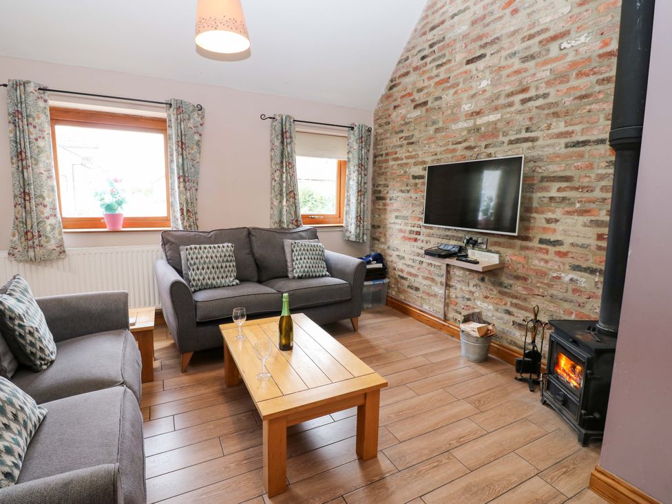 A living room with a sofa, coffee table, and television at Pottowe Cottage in Potto near Stokesley