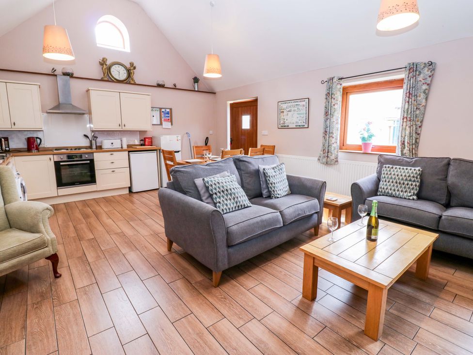 A living room with a sofa and kitchen cabinets at Pottowe Cottage in Potto near Stokesley