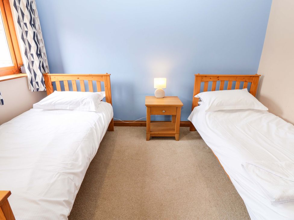 A bedroom with two beds and a nightstand at Pottowe Cottage in Potto near Stokesley