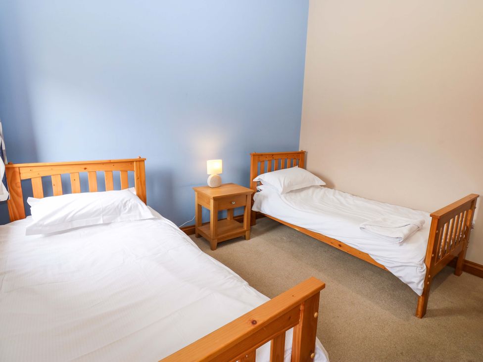 A bedroom with two beds and a nightstand at Pottowe Cottage in Potto near Stokesley