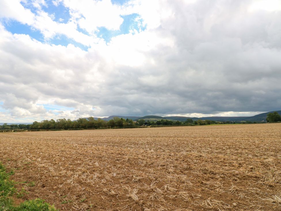 A field with trees and mountains under a cloudy sky at Pottowe Cottage in Potto near Stokesley